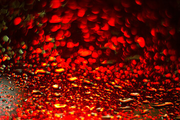Water drops in a windshield, reflecting red traffic lights