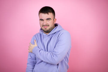 Young handsome man wearing casual sweatshirt over isolated pink background with pain on her shoulder and a painful expression