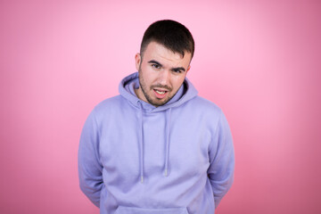 Obraz premium Young handsome man wearing casual sweatshirt over isolated pink background afraid and shocked with surprise and amazed expression, fear and excited face.