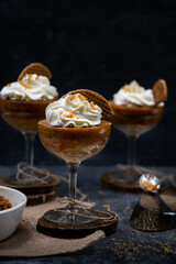 Pumpkin mousse and whipped cream served in tall glasses against black background, copy space