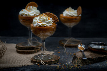 Pumpkin mousse and whipped cream served in tall glasses against black background