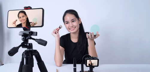 Asian teen woman sit in front of camera and live broadcasting as a beauty blogger influencer or...
