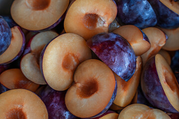 Food background of cutted halfs of blue plums. Top view with selective focus