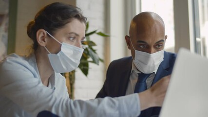 Business people with face masks working together on laptop in modern coworking office - Powered by Adobe