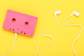 Earphones and cassette tape on yellow background