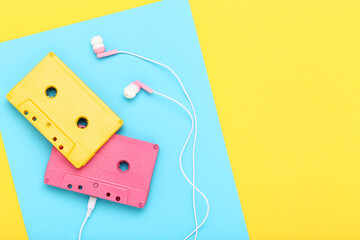 Earphones and cassette tapes on colorful background