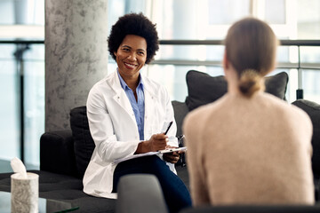 Happy black psychotherapist communicating with a patient during a session at the clinic.