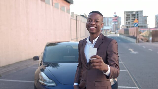Close Up confident african american man buy new car. Cheerful black businessman holds a modern electronic car key. Portrait of a successful man moving towards his goal buying an electric car to save
