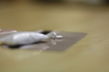 White drug pills, placed on top of a credit card, along with a bag of powdered cocaine to snort