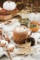 Fototapeta na wymiar Cup of coffee with cotton flowers, dry leafs, pumpkins and knitted sweater
