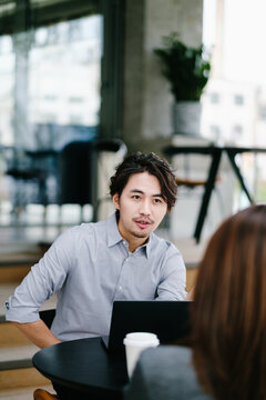 Businessman And Businesswoman Sitting In Cafe And Using Laptop