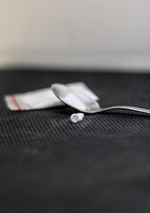 Close-up front view of some pills, placed in front of a teaspoon with cocaine on top, all placed on...