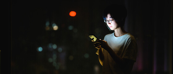 Girl using a phone at night by the window