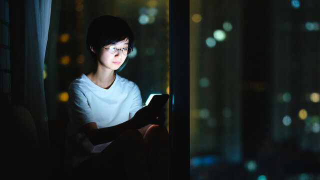 Girl using a phone at night by the window