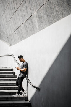 A Chinese Man Stretching With Mobile Phone After A Workout.