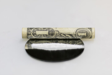 Close-up front close-up photo of a rolled up dollar bill, for snorting the cocaine powder strip...