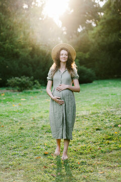 Barefooted pregnant woman on lawn in park