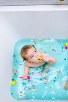 Sensory Bath Time Play for a baby and toddler with colorful pompons and blue water