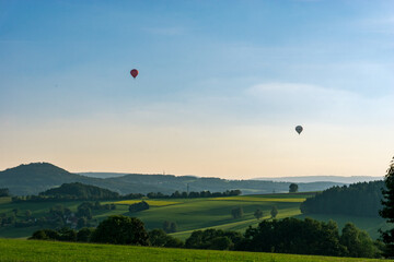 Two small hot air ballons over beautiful hilly landscape