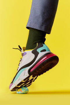 Foot in high fashion multi coloured trainer steps on the the world