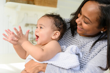Baby clapping in mother's arms after bath time