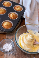 bowl of buttercream frosting and some cupcakes 