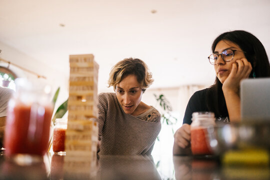 Young women having a drink at home while playing jenga