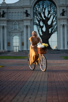 Young woman With A Flower Bouquet In Bicycle Basket