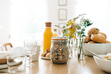 front shot of a breakfast brunch table with granola, pastries, cookies, orange juice and flowers