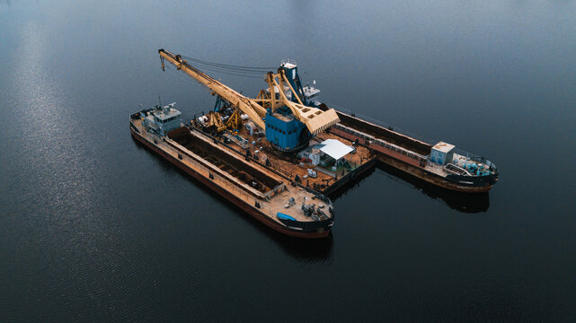 Floating crane at work. Loading empty cargos in the sea.