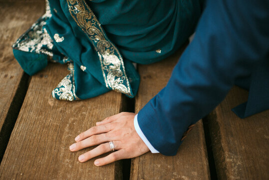 Indian bride and groom sitting next to each other outdoors on wooden jetty