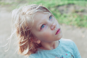 portrait of a cute little girl with a serious facial expression looking to the side and up