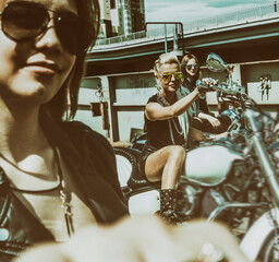 three sexy attractive young adult  blond and brunette women on large vintage classic motorcycle in...