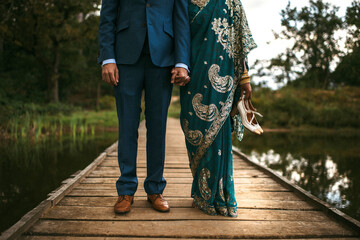 Indian bride and groom holding hands. Bride bare feet with shoes in hands