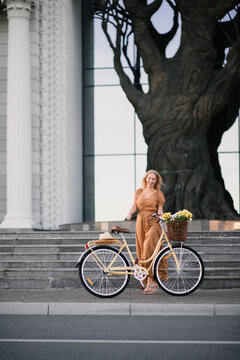 Young woman With A Flower Bouquet In Bicycle Basket