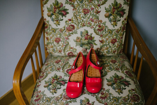 Red heels with bow on a vintage retro looking chair sofa indoors