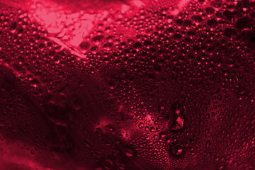 Abstract red background. Drops of water on the surface with glare.