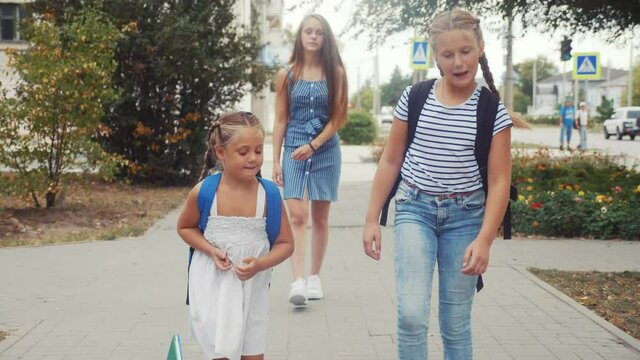 group of schoolchildren walking to school along the path. happy family school concept. little girl schoolgirl dropped a textbook. schoolgirls walk along in the park to school for education lessons