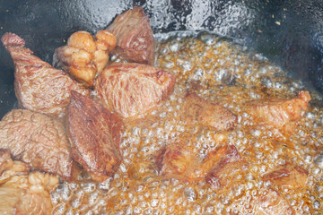Cooking pilaf in a cauldron on the grill outside in the summer