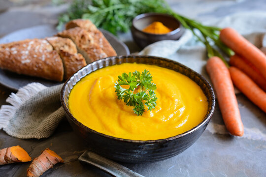 Delicious creamy carrot soup with turmeric powder and baguette