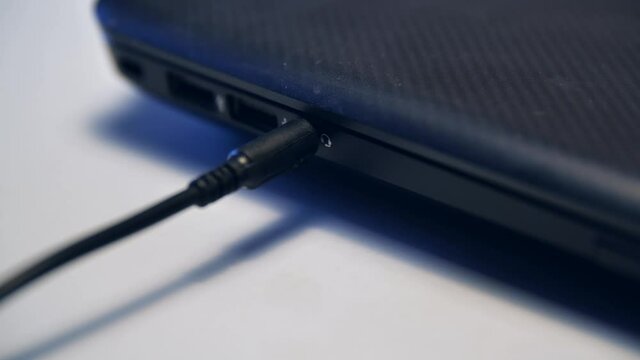 Close up of male hand inserting headphones cable into computer or laptop port. Media. Connecting cable to device isolated on white background.