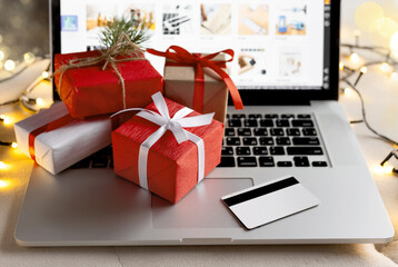 Gifts and credit card on the laptop with blurred bokeh lights. Christmas online shopping, sales and discounts promotions during the Christmas holidays, online shopping at home and lockdown coronavirus