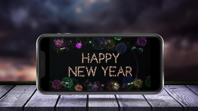 Digital animation of happy new year text and fireworks exploding on smartphone screen