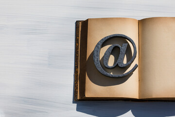 開かれたアンティーク本の上のアットマーク