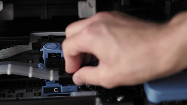 Video instruction, technology, press, media, office, stationery concept - close-up of male hands preparing new inkjet printer for launch. step 5: closing black cartridge locking cover and push it down