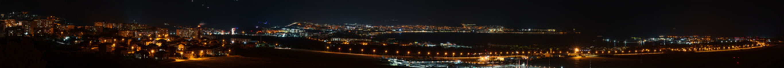 Fototapeta na wymiar Big night panorama of Gelendzhik city resort bay at night, Russia with many illuminated buildings, hotels and airport. Black sea town for rest, vacation and holidays.