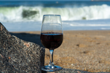 Tasting of different fortified dessert ruby, tawny port wines in glasses on sandy beach with view on waves of Atlantic ocean near Vila Nova de Gaia and city of Porto, Portugal