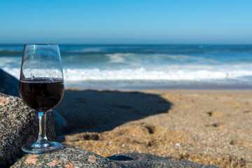 Tasting of different fortified dessert ruby, tawny port wines in glasses on sandy beach with view on waves of Atlantic ocean near Vila Nova de Gaia and city of Porto, Portugal