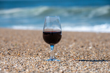 Tasting of different fortified dessert ruby, tawny port wines in glasses on sandy beach with view on waves of Atlantic ocean near Vila Nova de Gaia and city of Porto, Portugal