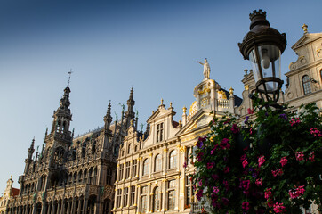 Fototapeta na wymiar Brussels, Belgium, August 2019. The Great Square or Grote Markt. The evening light enhances its beauty of the magnificent Baroque and Gothic buildings. A lamppost decorated with a planter is the frame
